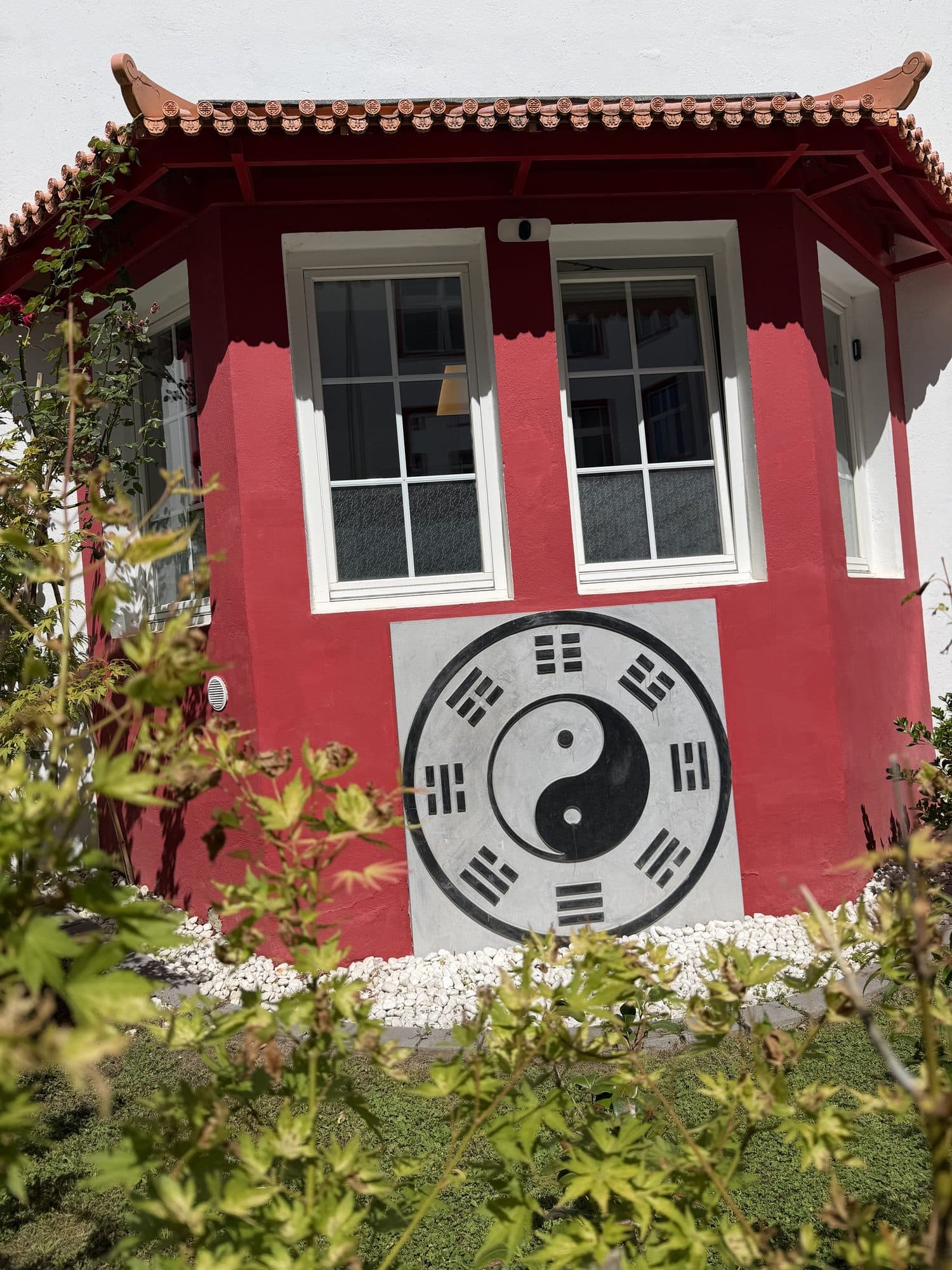 Roter Pavillon im Innenhof mit großem Yin-Yang- und Bagua-Zeichen an der Wand