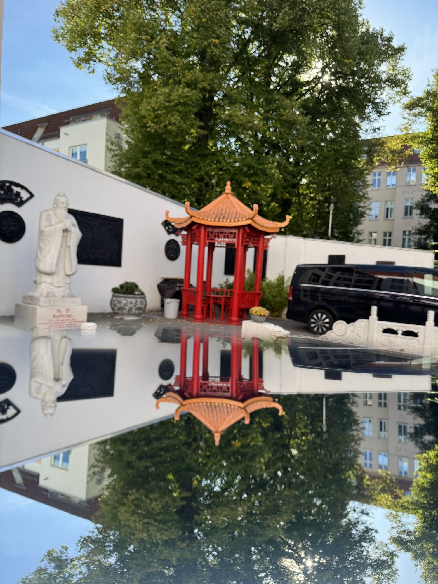 Roter chinesischer Pavillon, der sich im Wasserbecken des Innenhofs spiegelt