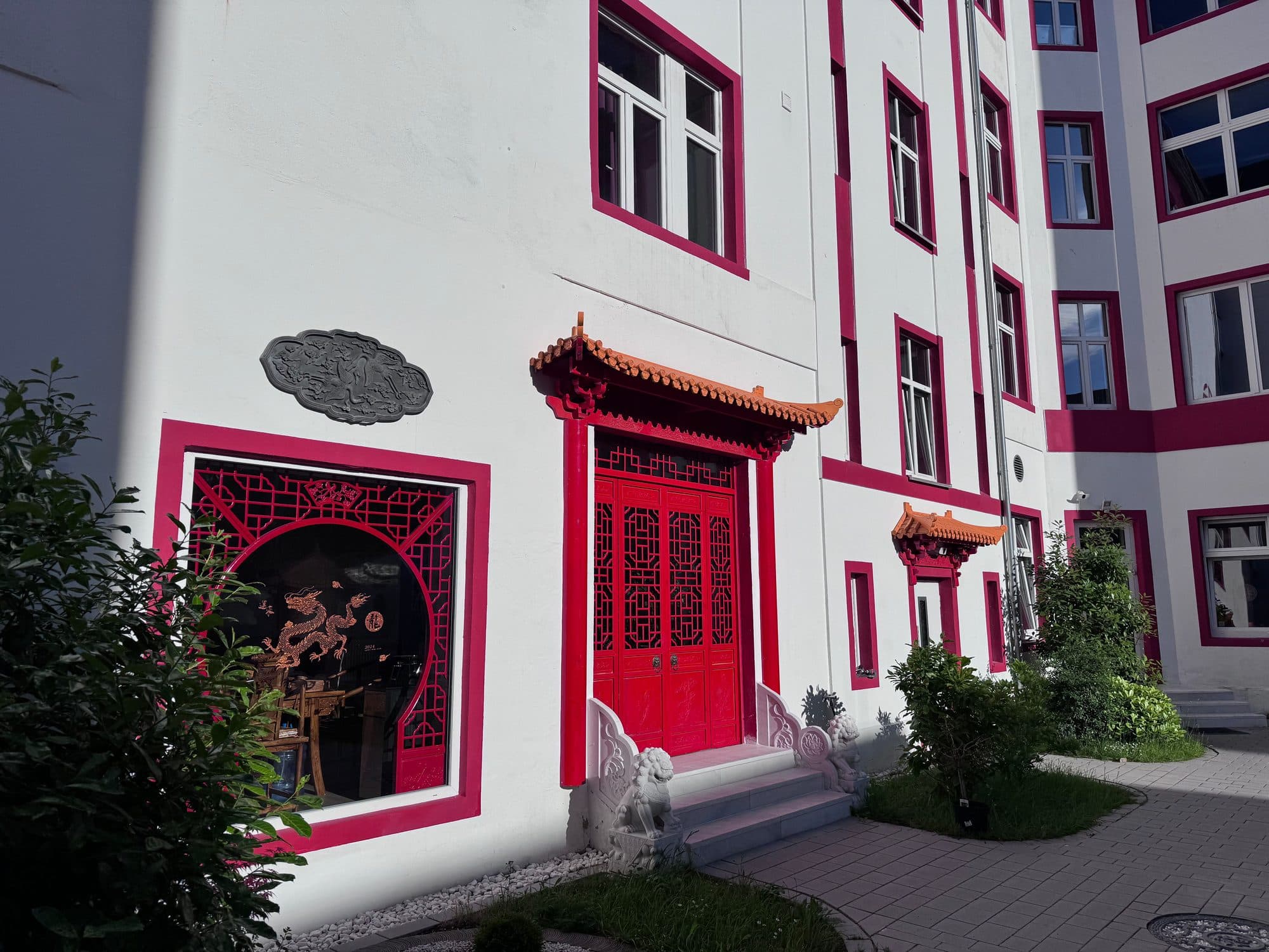 Rote Flügeltür mit geschwungenem Pagodendach und rundem Zierfenster