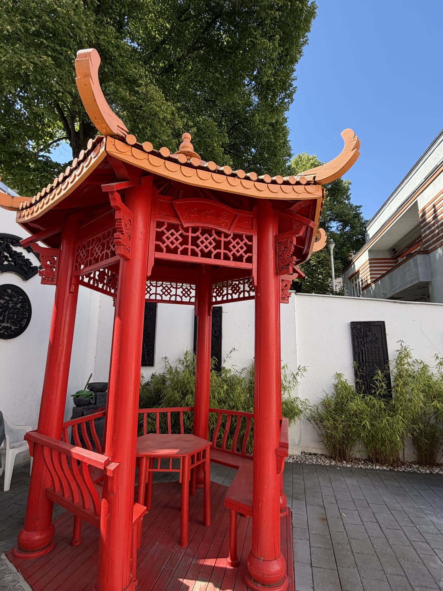 Roter chinesischer Pavillon mit Sitzgelegenheiten im Innenhof